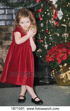 a young girl holds an ornament as she stands by the christmas tree View Large Photo Image Stock Image - a young girl holds an ornament as she stands by the christmas tree. Fotosearch