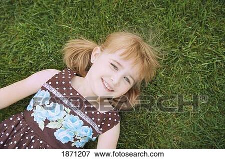Stock Photo - a young girl laying on the grass. Fotosearch