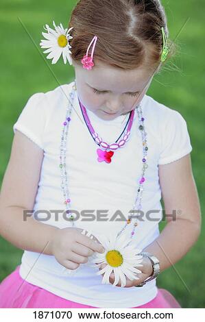 Stock Image - a young girl pulling petals from a daisy. Fotosearch