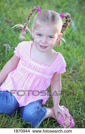 Picture - a young girl sitting on the grass. Fotosearch