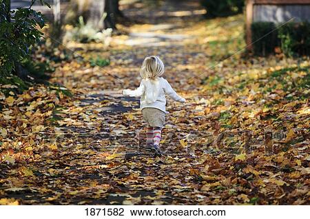Stock Image - a young girl walks down a path in autumn. Fotosearch