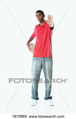 a young man holding out his hand to say stop with a heart held behind his back View Large Photo Image Stock Photo - a young man holding out his hand to say stop with a heart held behind his back. Fotosearch