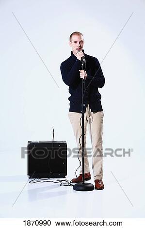 Stock Image - a young man singing into a microphone. Fotosearch