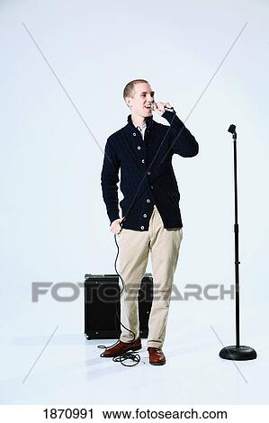 Stock Image - a young man singing into a microphone. Fotosearch