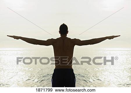Stock Photo - a young man with arms out over the water. Fotosearch