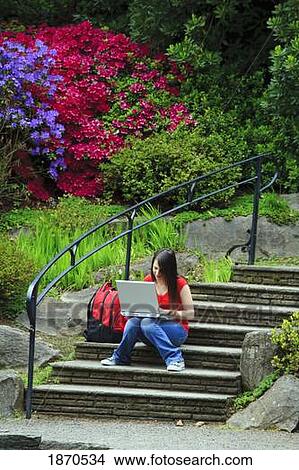 a young woman working on her laptop while sitting outside on some steps View Large Photo Image Picture - a young woman working on her laptop while sitting outside on some steps. Fotosearch