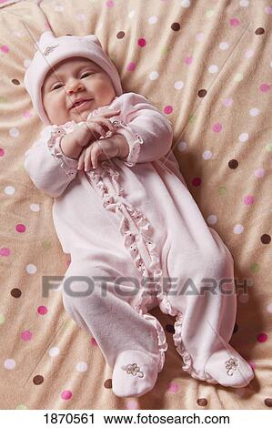 Stock Image - an infant girl wearing a sleeping with frills and a cap. Fotosearch