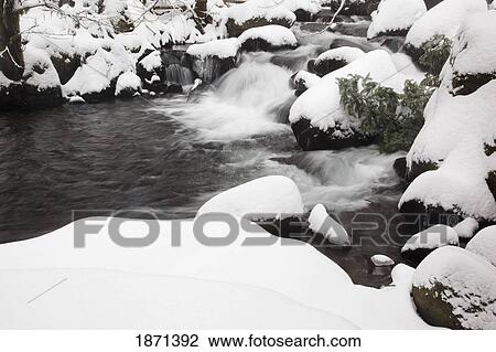 Stock Image - columbia river gorge national scenic area, oregon, united states of america; snow covering the rocks in a creek. Fotosearch