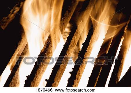 Stock Photograph - flames coming up between the grill. Fotosearch