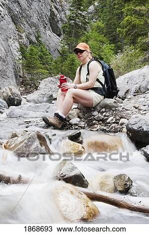 kananaskis country, alberta, canada; a female hiker sitting on the creek bank with a water bottle View Large Photo Image Stock Image - kananaskis country, alberta, canada; a female hiker sitting on the creek bank with a water bottle. Fotosearch