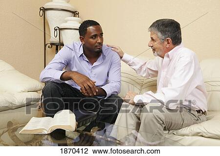 Stock Image - men talking together with a bible open. Fotosearch