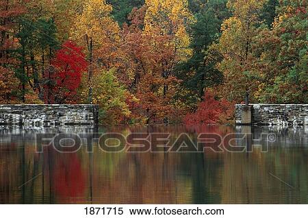 Stock Photography - north carolina, united states of america; autumn colored trees and stone dam wall reflected in a lake at hanging rock state park. Fotosearch