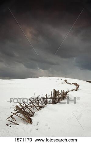 Stock Image - south shields, tyne and wear, england; a fence in a snowy field with a dark sky. Fotosearch