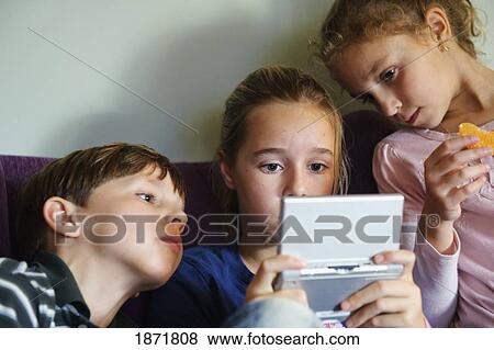 three children looking at a digital handheld game View Large Photo Image Stock Photo - three children looking at a digital handheld game. Fotosearch