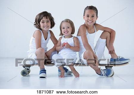 Stock Photo - three young girls sitting on a long board. Fotosearch