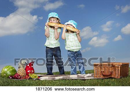 two young girls eating a big loaf of bread at a picnic View Large Photo Image Stock Photograph - two young girls eating a big loaf of bread at a picnic. Fotosearch