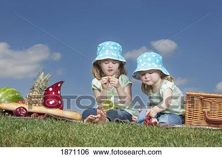 Stock Photograph - two young girls eating at a picnic. Fotosearch