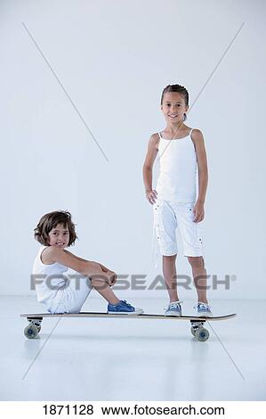 two young girls on a longboard View Large Photo Image Stock Photo - two young girls on a longboard. Fotosearch
