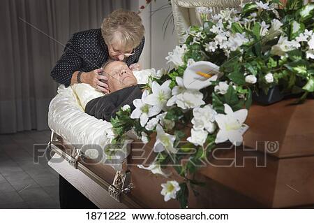 Stock Image - woman kisses her deceased spouse in a coffin. Fotosearch