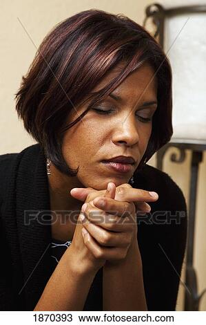 Stock Image - woman praying with hands clasped. Fotosearch
