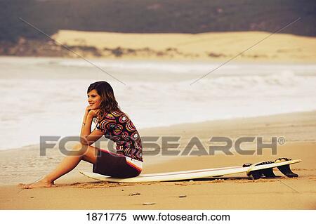 young woman sitting on her surf board on the beach View Large Photo Image Stock Photography - young woman sitting on her surf board on the beach. Fotosearch