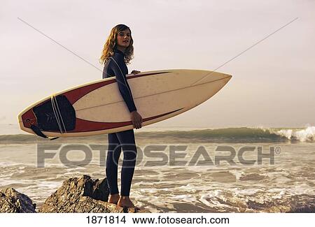 Picture - young woman with her surfboard at the beach. Fotosearch