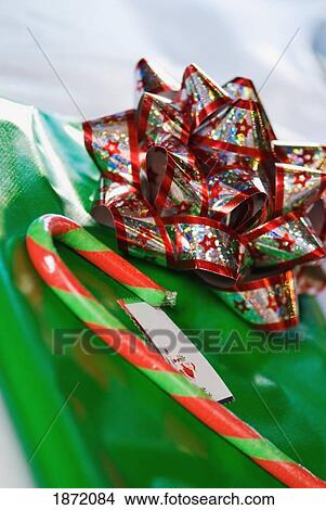 Picture - a bow and candy cane on a gift. Fotosearch