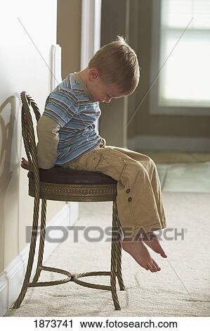 a boy sitting on a chair looking sad View Large Photo Image Stock Image - a boy sitting on a chair looking sad. Fotosearch