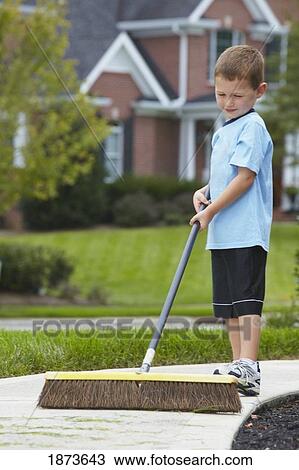 Stock Image - a boy sweeping the sidewalk with a broom. Fotosearch