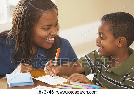 Stock Photograph - a boy writing cards with his mother. Fotosearch