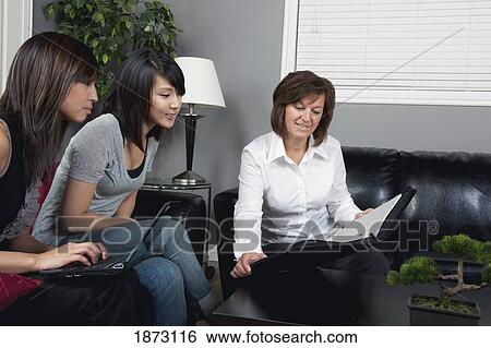 Stock Photograph - a businesswoman showing a document to two young women. Fotosearch