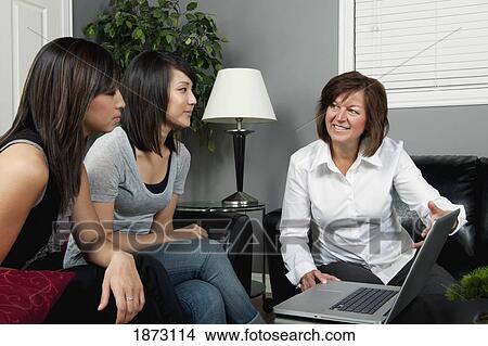 a businesswoman showing something to two young women on her laptop computer View Large Photo Image Picture - a businesswoman showing something to two young women on her laptop computer. Fotosearch