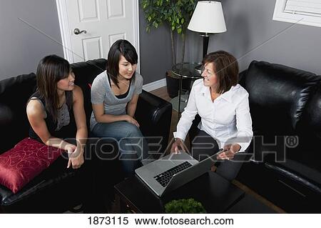 a businesswomen showing something to two young women on her laptop computer View Large Photo Image Stock Photography - a businesswomen showing something to two young women on her laptop computer. Fotosearch