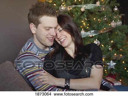 Picture - a couple by the christmas tree. Fotosearch