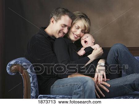 a family sitting on a couch with a baby yawning View Large Photo Image Stock Image - a family sitting on a couch with a baby yawning. Fotosearch