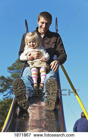 a father and daughter going down a slide together at the playground View Large Photo Image Stock Photo - a father and daughter going down a slide together at the playground. Fotosearch