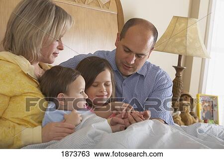 Stock Image - a father and mother praying with their children at bedtime. Fotosearch