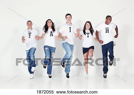 Stock Photography - a group of teenagers holding hands and jumping in the air wearing t-shirts with the message 'faith'. Fotosearch