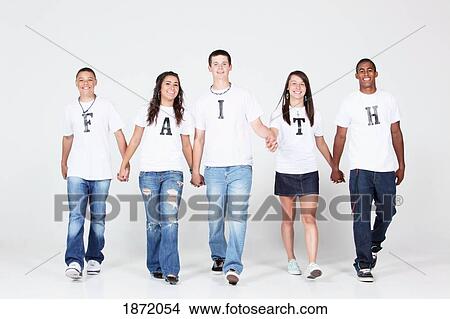 Picture - a group of teenagers holding hands wearing t-shirts with the message 'faith'. Fotosearch