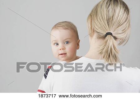 a toddler boy looking over his mother's shoulder View Large Photo Image Stock Photo - a toddler boy looking over his mother's shoulder. Fotosearch