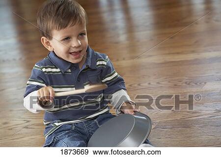 a young boy playing with a cake pan View Large Photo Image Stock Photo - a young boy playing with a cake pan. Fotosearch