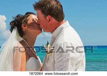 Picture - akumal, riviera maya, mexico; a bride and groom kiss on the beach at gran bahia principe tulum all-inclusive resort. Fotosearch