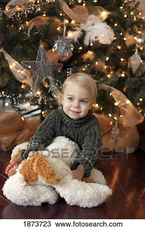 Stock Image - jordan, ontario, canada; a toddler sitting beside the christmas tree. Fotosearch