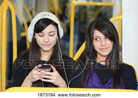 Picture - portland, oregon, united states of america; two teenage girls listening to music by sharing ear buds. Fotosearch