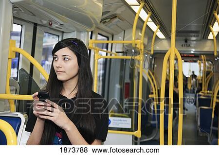 Stock Photo - portland, oregon, united states of america; a teenage girl using her cell phone while sitting on public transportation. Fotosearch