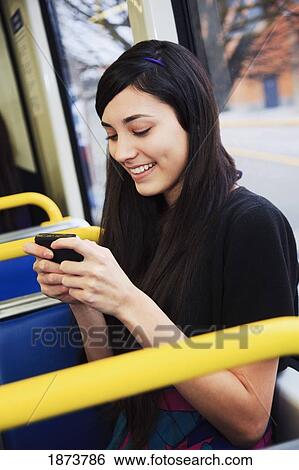 Stock Photograph - portland, oregon, united states of america; a teenage girl using her cell phone while sitting on public transportation. Fotosearch