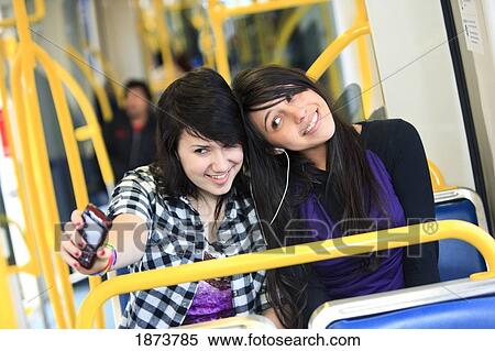 Stock Photography - portland, oregon, united states of america; two teenage girls listening to music by sharing ear buds. Fotosearch