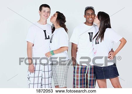 teenage couples wearing t-shirts with the message love and the girls kissing the boy's cheeks View Large Photo Image Stock Image - teenage couples wearing t-shirts with the message love and the girls kissing the boy's cheeks. Fotosearch