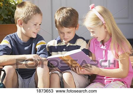 Stock Image - three children reading a book. Fotosearch