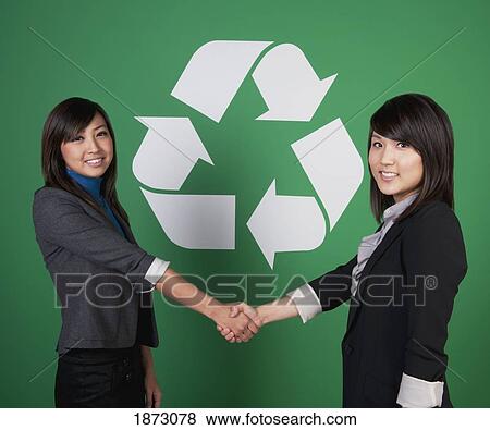 two businesswomen shaking hands in front of a recycle symbol View Large Photo Image Stock Photo - two businesswomen shaking hands in front of a recycle symbol. Fotosearch